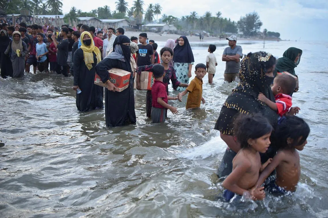 Rohingya Muslims return to their wooden boat after receiving water and food in Ulee Madon beach in North Aceh.