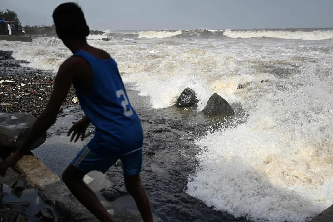 A boy moves away from the seafront as high tidal waves hit the coast in Mumbai on June 13, 2023, as cyclone Biparjoy makes its way across the Arabian Sea towards the coastlines of India and Pakistan. (Photo by Punit PARANJPE / AFP)