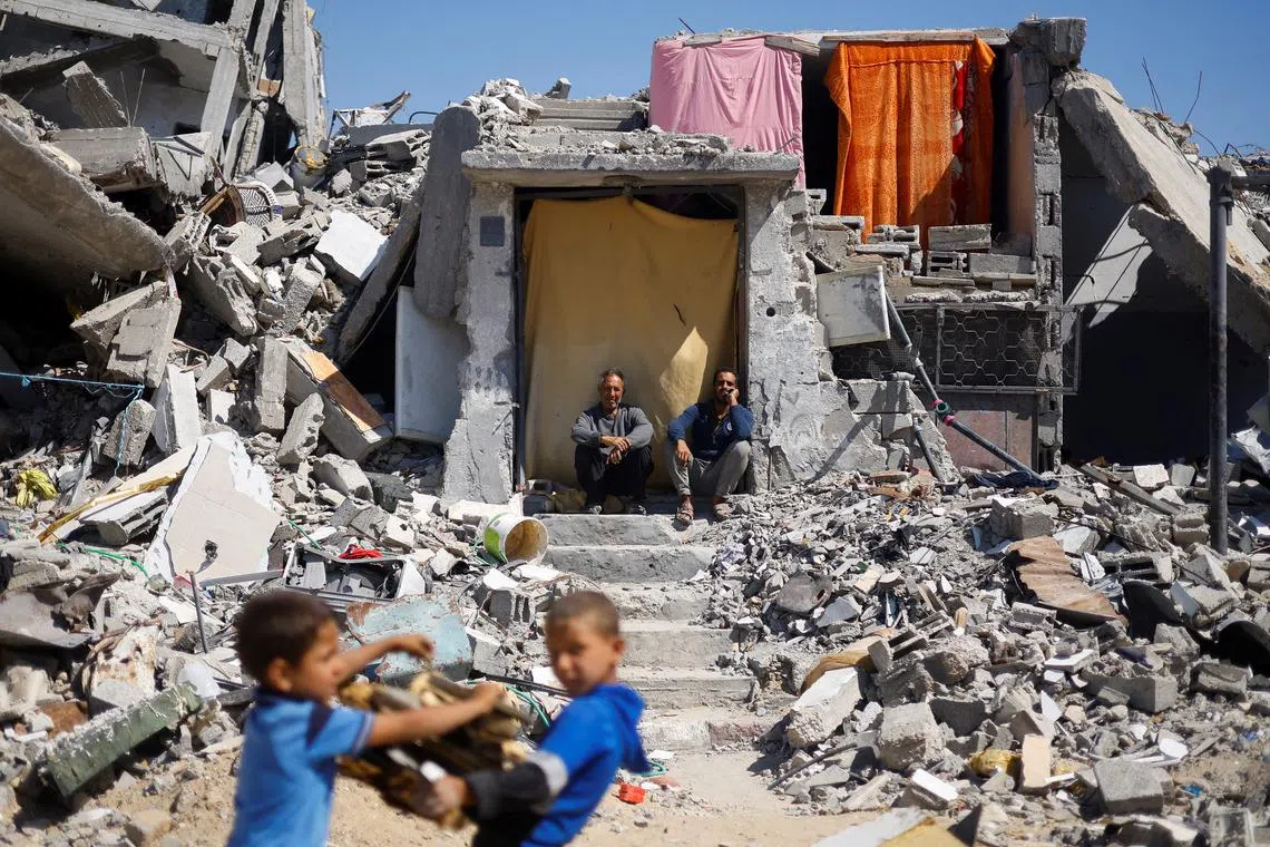 FILE PHOTO: Palestinians sit at their house which was destroyed in an Israeli strike, amid the ongoing conflict between Israel and Hamas, in Khan Younis, in the southern Gaza Strip May 14, 2024. REUTERS/Mohammed Salem/File Photo