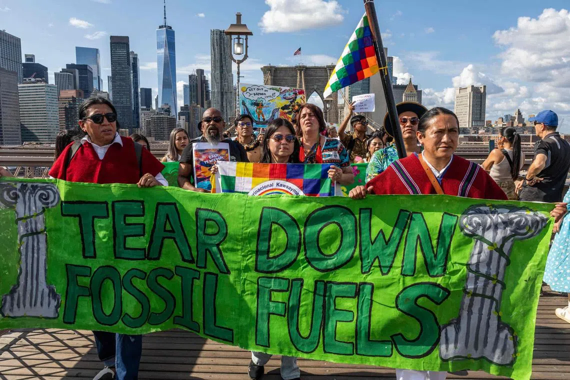 TOPSHOT - People cross the Brooklyn Bridge calling for leaders to “Tear down the pillars of fossil fuels” during a Youth Global Climate demonstration ahead of the UN Climate week and General Assembly in New York City on September 20, 2024. (Photo by Alex KENT / AFP)