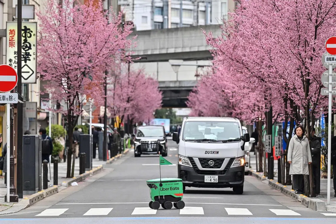 An unmanned robot navigates a street during a demonstration of a robot delivery service by Uber Eats Japan, Mitsubishi Electric and robot developer Cartken in downtown Tokyo on March 5, 2024.