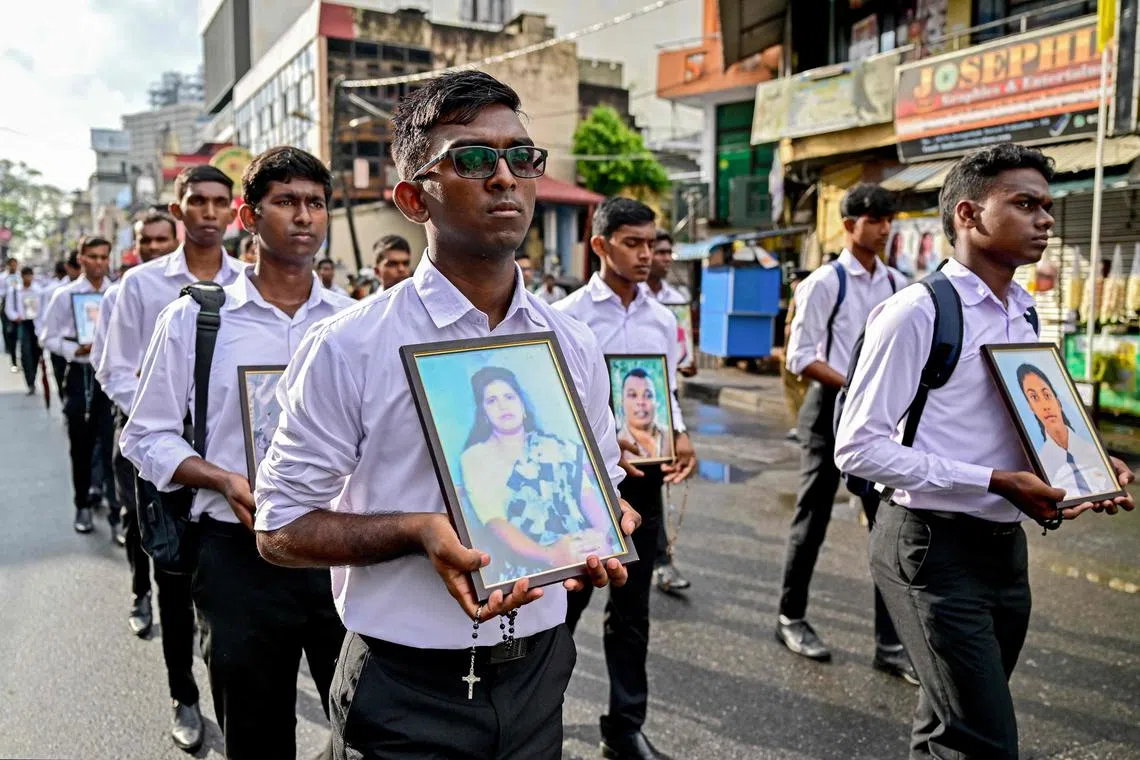 Men carry portraits of victims of the 2019 Easter Sunday bombings as they pay tribute to mark the 6th anniversary of the suicide attacks, during a silent march outside the St. Anthony's church in Colombo on April 21, 2025. The head of Sri Lanka's Roman Catholic church, Cardinal Malcolm Ranjith, led the march in the capital where he presided over a multi-religious ceremony for the 279 victims, including 45 foreigners. Several investigations into the bombings have concluded that the attacks were carried out by a homegrown jihadist group that claimed affiliation with the Islamic State group. (Photo by Ishara S. KODIKARA / AFP)