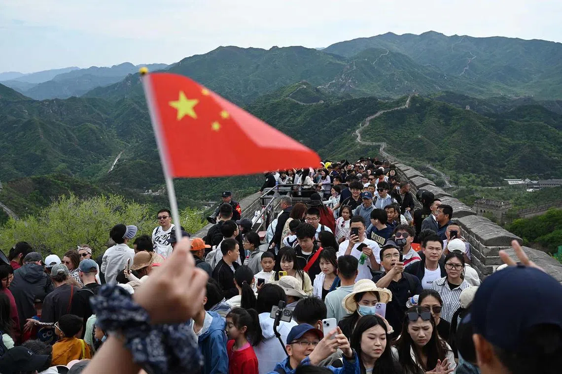 TOPSHOT - People climb the Great Wall of China at Badaling, north of Beijing, on May 1, 2025, the first day of a 5-day national May Day holiday. (Photo by GREG BAKER / AFP)