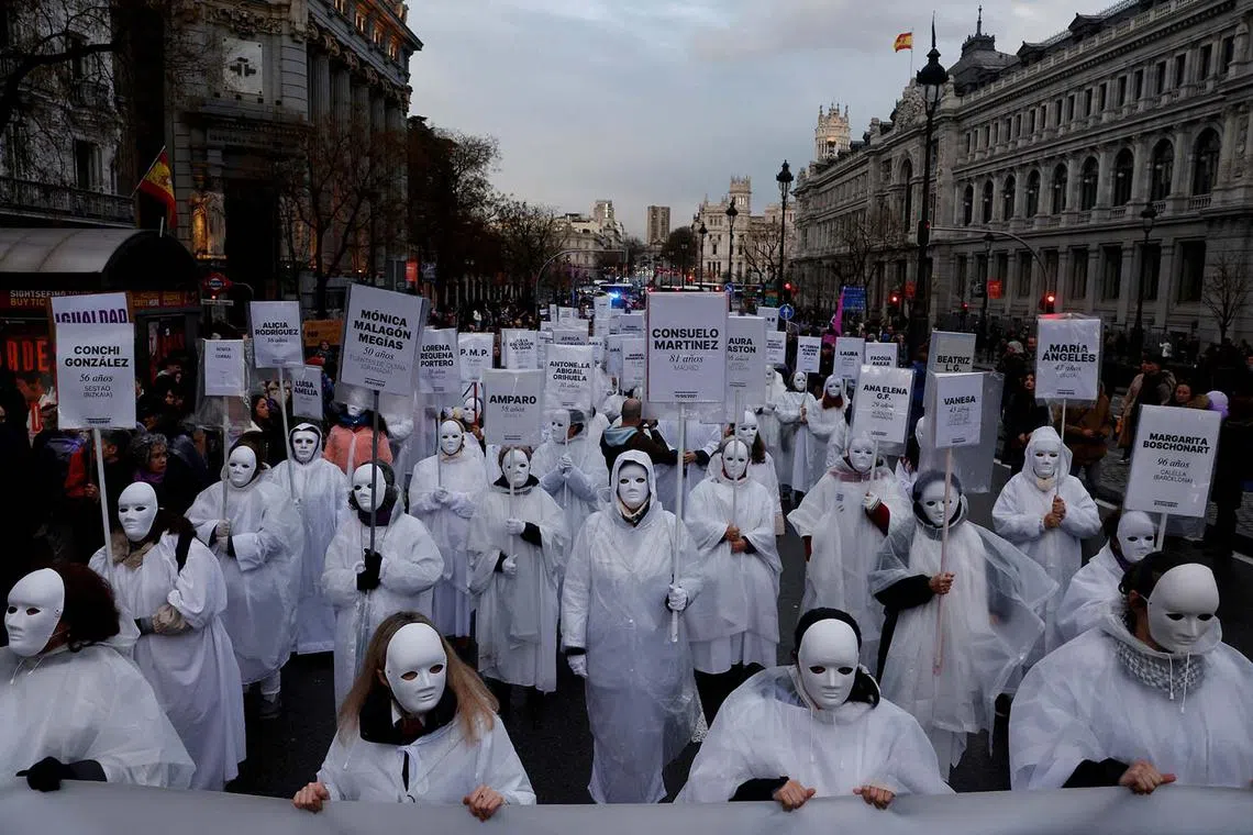 Women wearing masks hold signs with the names of those who, according to them, are victims of gender-based violence, during a demonstration to mark International Women's Day in Madrid, Spain, March 8, 2025. 