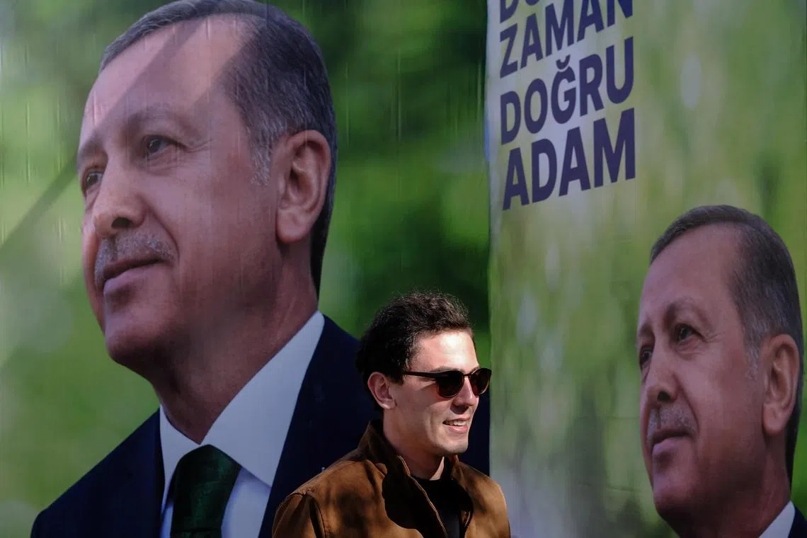 A man walks in front of pictures of Turkish President Recep Tayyip Erdogan, in Istanbul, Turkey, ahead of a May 14 vote.