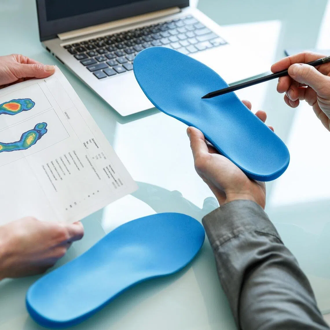 Doctor consulting patient on custom orthotic insoles in a clinic for a personalised custom fit.
