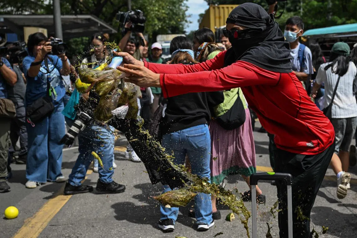 A protester throws a balloon filled with dirty water during an anti-corruption rally in Manila.