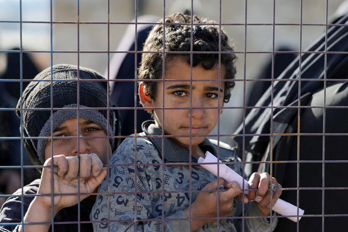 Children, part of a group of detainees, look through a fence at al-Hol camp after the Syrian government took control of it following the withdrawal of Syrian Democratic Forces (SDF), in Hasaka, Syria, January 21, 2026. REUTERS/Khalil Ashawi
