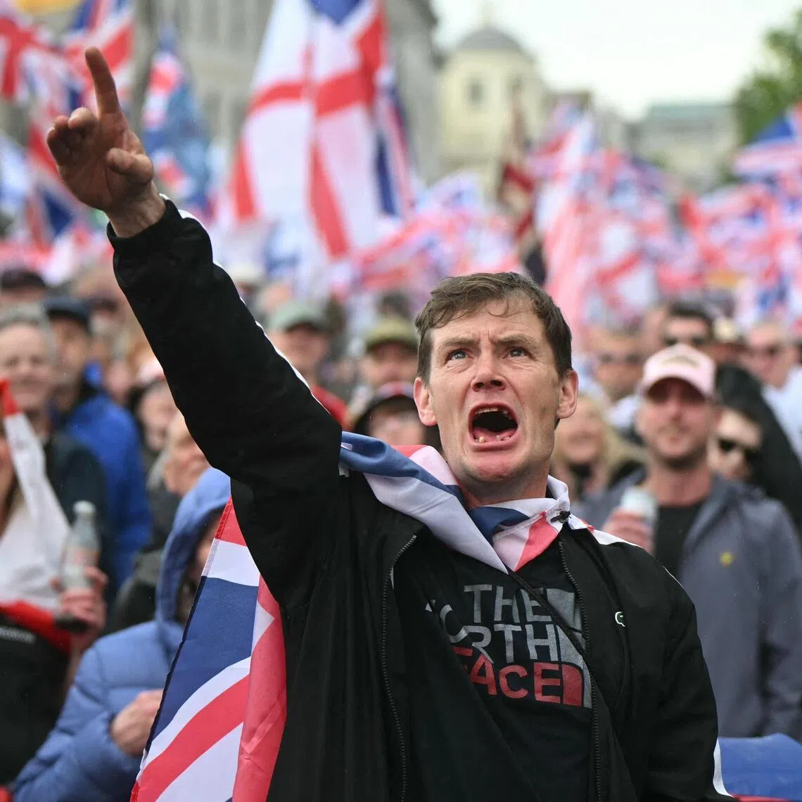 Supporters of British far-right activist Tommy Robinson watch the speeches on screens after taking part in a march organised by Unite The Kingdom, in central London on May 16.