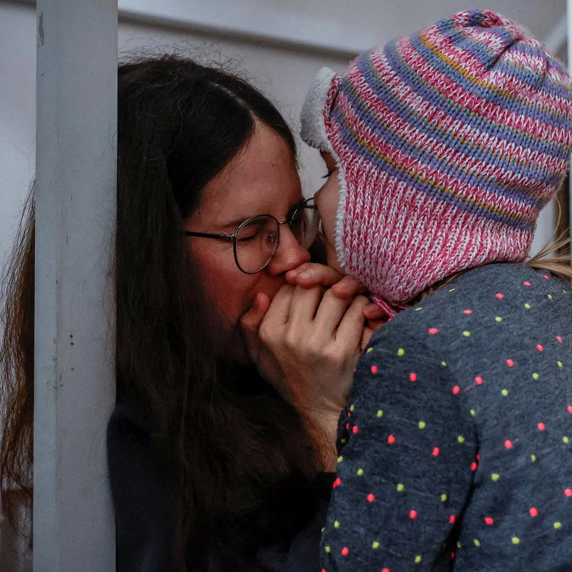 Yuliia Chumak, who is eight months pregnant, warms her daughter’s hands with her breath, as they get ready to leave for kindergarten during power cuts after critical civil infrastructure was hit by recent Russian missile and drone strikes, in Kyiv, Ukraine, January 14. REUTERS/Alina Smutko