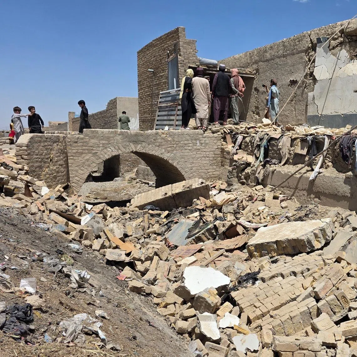 People stand on the rubble of a damaged building that, according to locals residents was damaged in a cross-border shelling by Afghanistan, in Chaman, Balochistan Province, Pakistan on April 28.