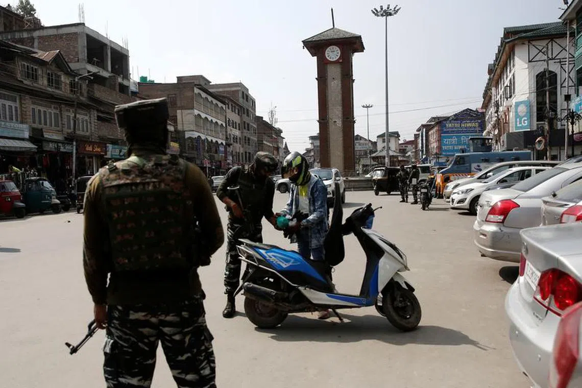 Indian Central Reserve Police Force (CRPF) personnel check the bags of a scooterist as part of security checking in Srinagar, October 12, 2021. REUTERS/Danish Ismail/File Photo