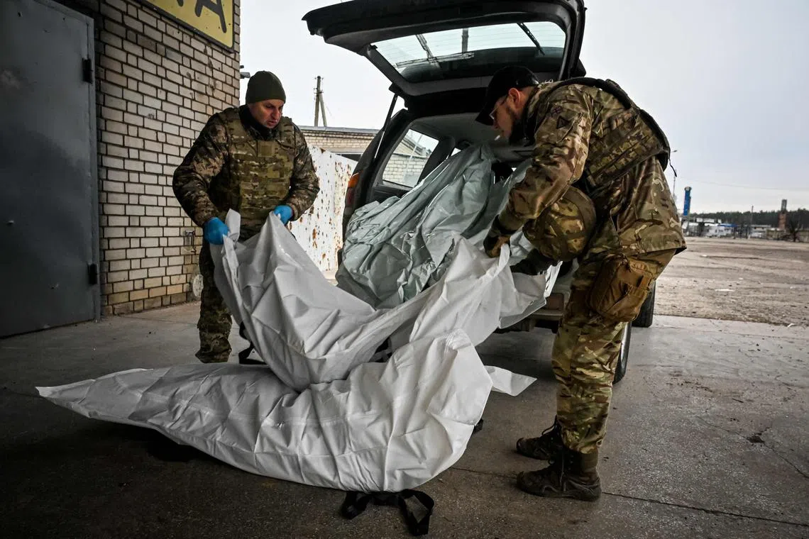 Ukrainian servicemen unload plastic bags containing the bodies of killed Russian soldiers from a liberated village near Kupiansk, in Ukraine's Kharkiv region, on Dec 15, 2022.