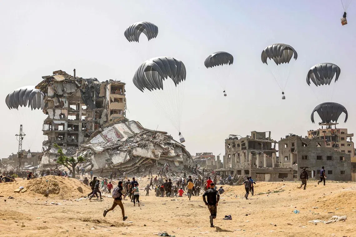 People rush to landing humanitarian aid packages dropped over the northern Gaza Strip on April 23.