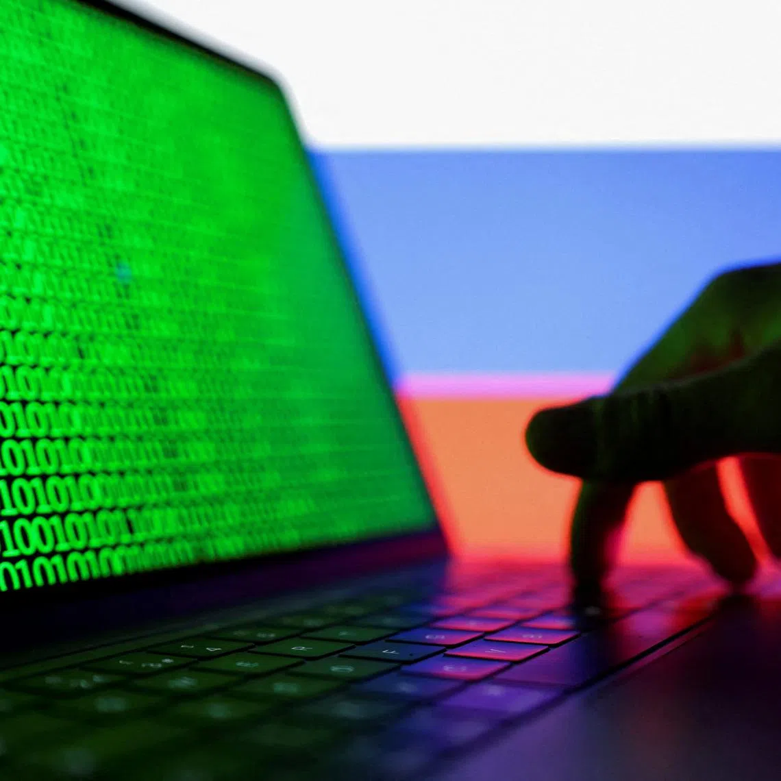 FILE PHOTO: A hand is seen on a laptop with binary code displayed on the screen in front of a Russian flag in this picture illustration created on August 19, 2022. REUTERS/Dado Ruvic/Illustration/File Photo