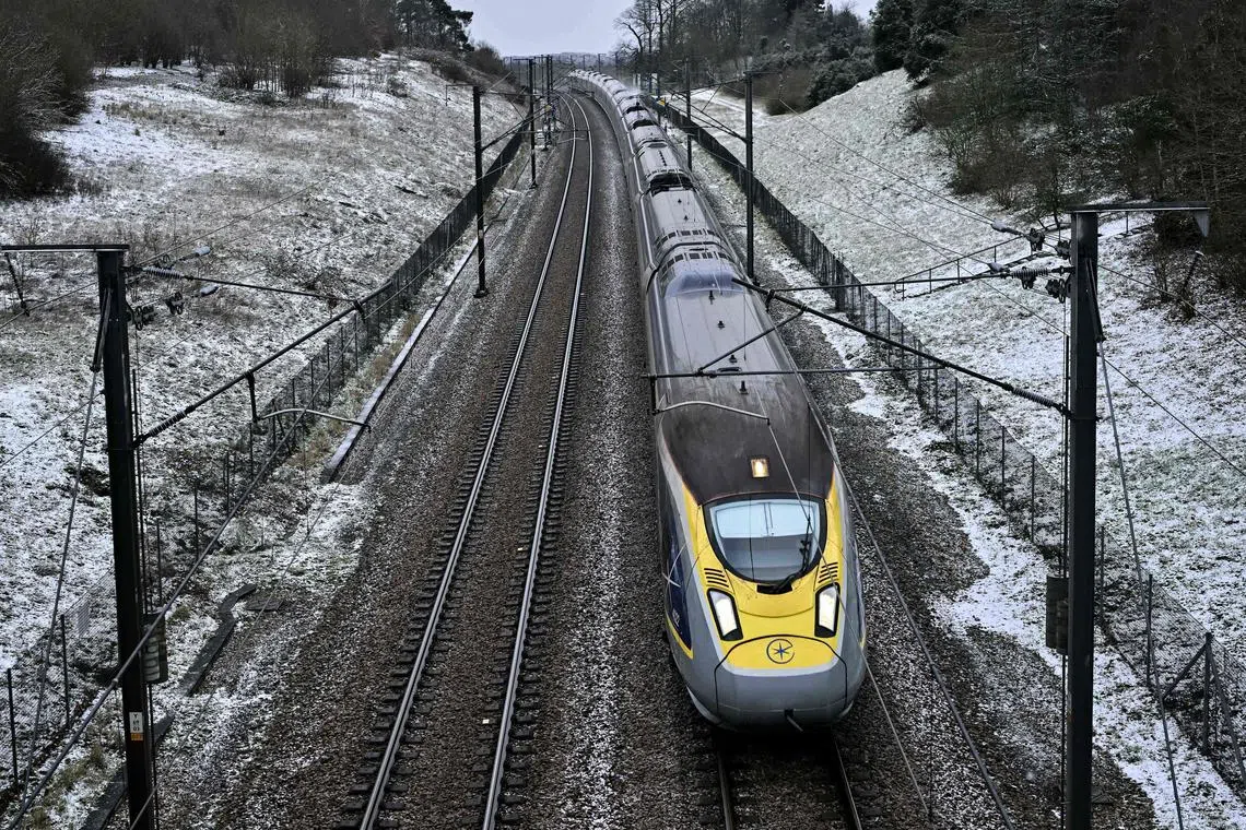 (FILES) A Eurostar train coming from Gare du Nord in Paris passes by trees and grass covered in snow near Maidstone, southern England, on January 8, 2024. Many travellers are now opting to take the plane between London and Paris, despite a speedy rail service connecting the two capitals in just over two hours and climate change concerns. (Photo by Ben Stansall / AFP)