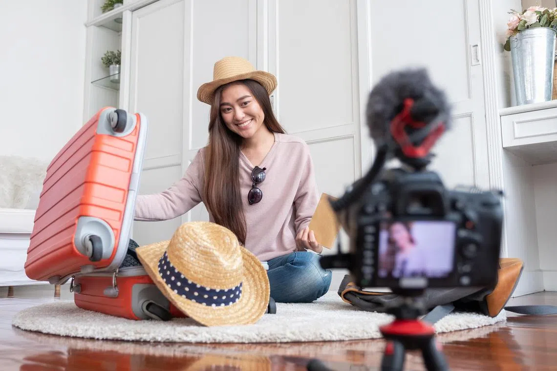 Asian young female blogger recording vlog video with vacation preparing to travel trip at home.online influcencer on social media concept