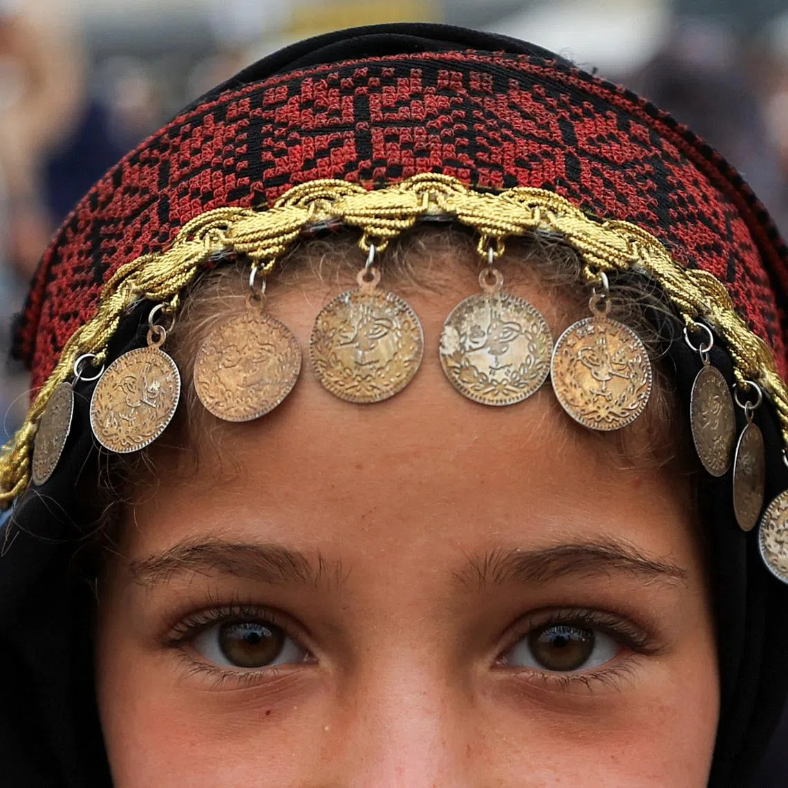 A Palestinian girl, wearing traditional headwear, posing for a photograph on Eid al-Adha, in Gaza City, on May 27, 2026. 
