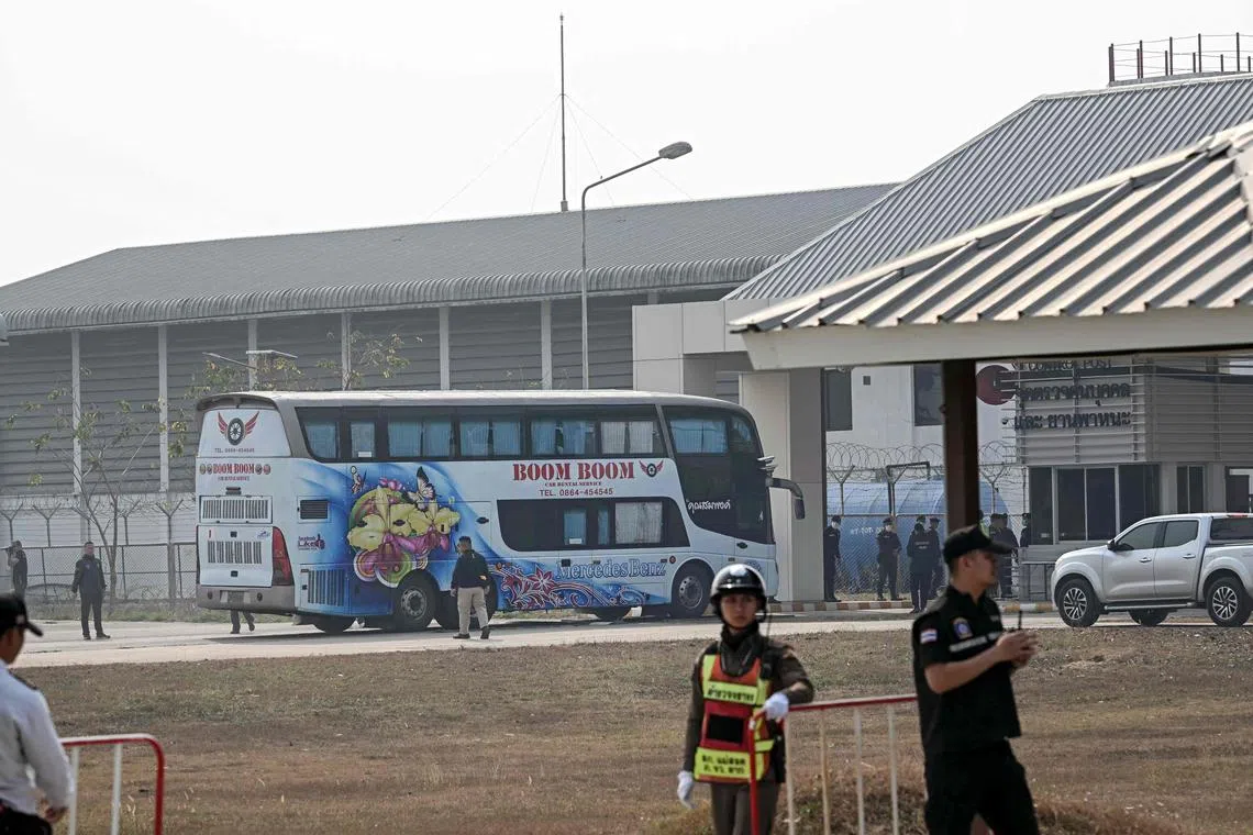A bus carrying alleged scam centre workers and victims from China handed over from Myanmar arrives at Mae Sot airport.
