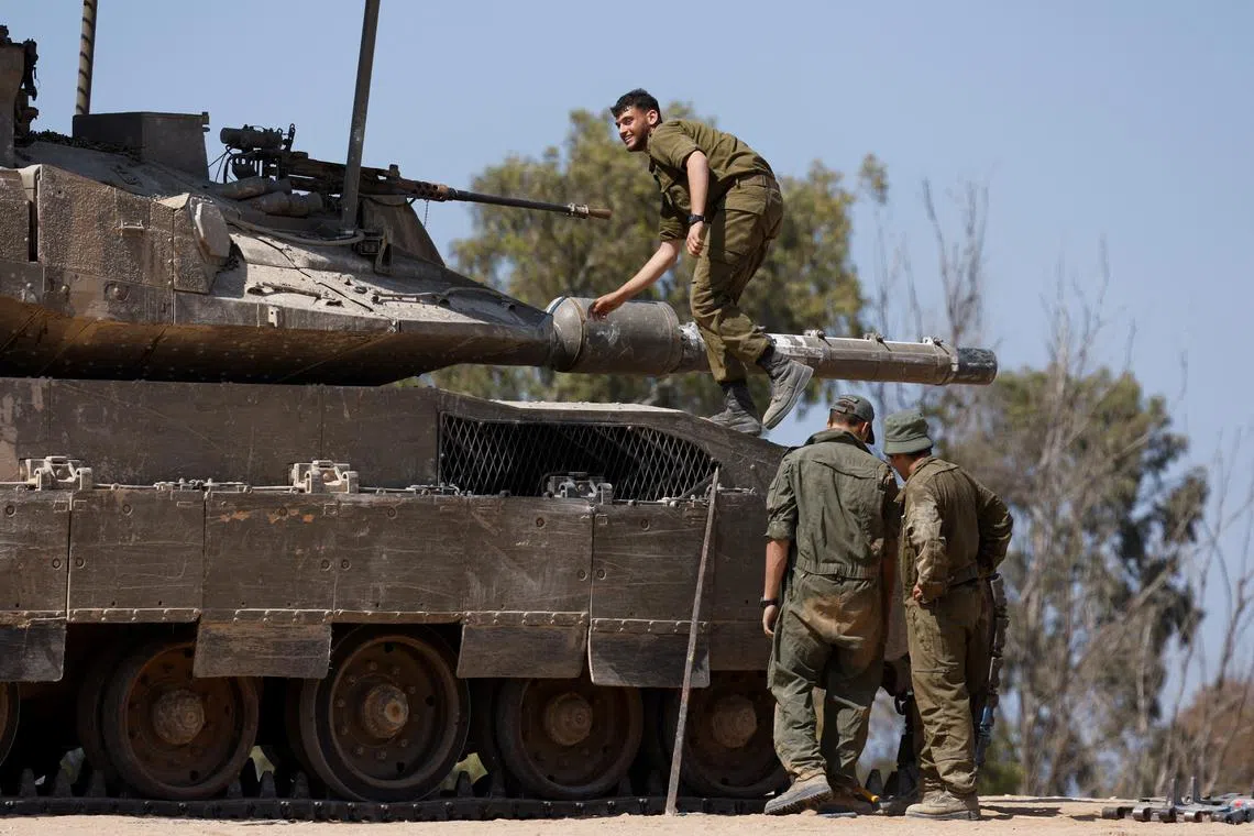 Israeli soldiers stand next to a tank, near the Israel-Gaza border, amid the ongoing conflict between Israel and the Palestinian Islamist group Hamas, in Israel, April 15, 2024. REUTERS/Amir Cohen/File Photo