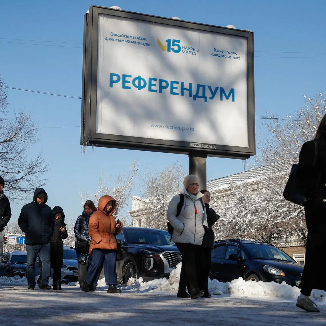 People walk past a campaign poster for a referendum on a new constitution in Almaty, Kazakhstan, March 12, 2026.  REUTERS/Pavel Mikheyev