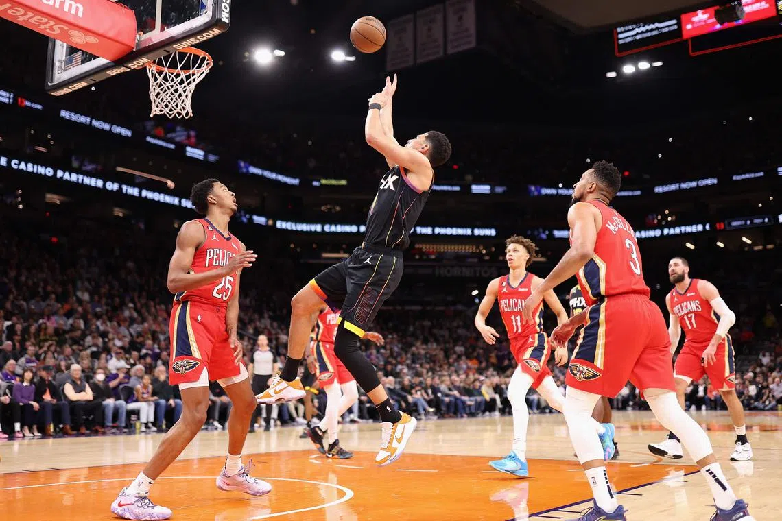 The Phoenix Suns' Devin Booker attempts a shot over Trey Murphy of the New Orleans Pelicans during the first half of their NBA game at Footprint Centre.