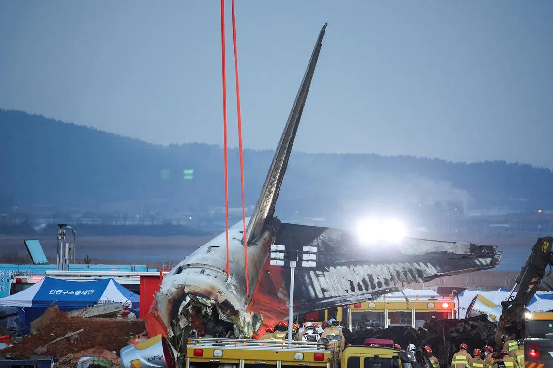 Efforts are made to lift the wreckage of an aircraft lying on the ground after it went off the runway and crashed at Muan International Airport, in Muan, South Korea, December 29, 2024. REUTERS/Kim Hong-Ji