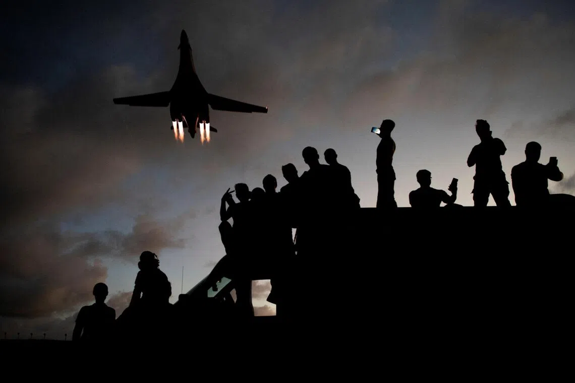 US Air Force mechanics taking selfies as a B-1B bomber flies overhead at Andersen Air Force Base in Guam, in the western Pacific Ocean, in 2020.