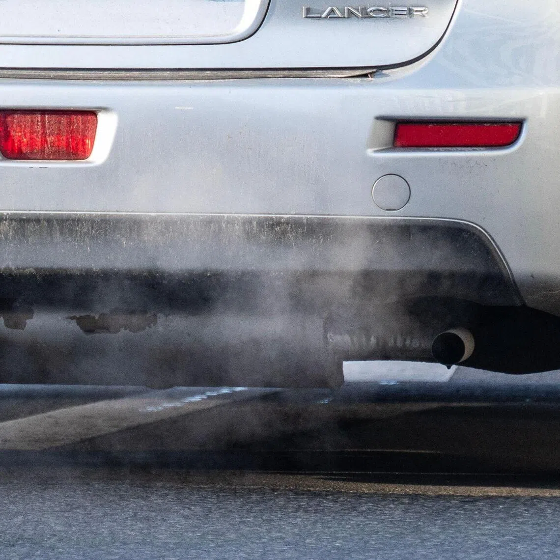 An exhaust pipe of a car with a combustible engine expels fumes in Berlin on December 16, 2025. The European Union looks set to scrap a landmark 2035 ban on new petrol and diesel cars on December 16, as part of a package of reforms aimed at supporting Europe's embattled auto industry. The ban was hailed as a major win in the fight against climate change when it was adopted in 2023, but carmakers and their backers have lobbied hard over the past year for Brussels to relax it, in the face of fierce competition from China and a slower-than-expected shift to electric vehicles (EVs). (Photo by John MACDOUGALL / AFP)