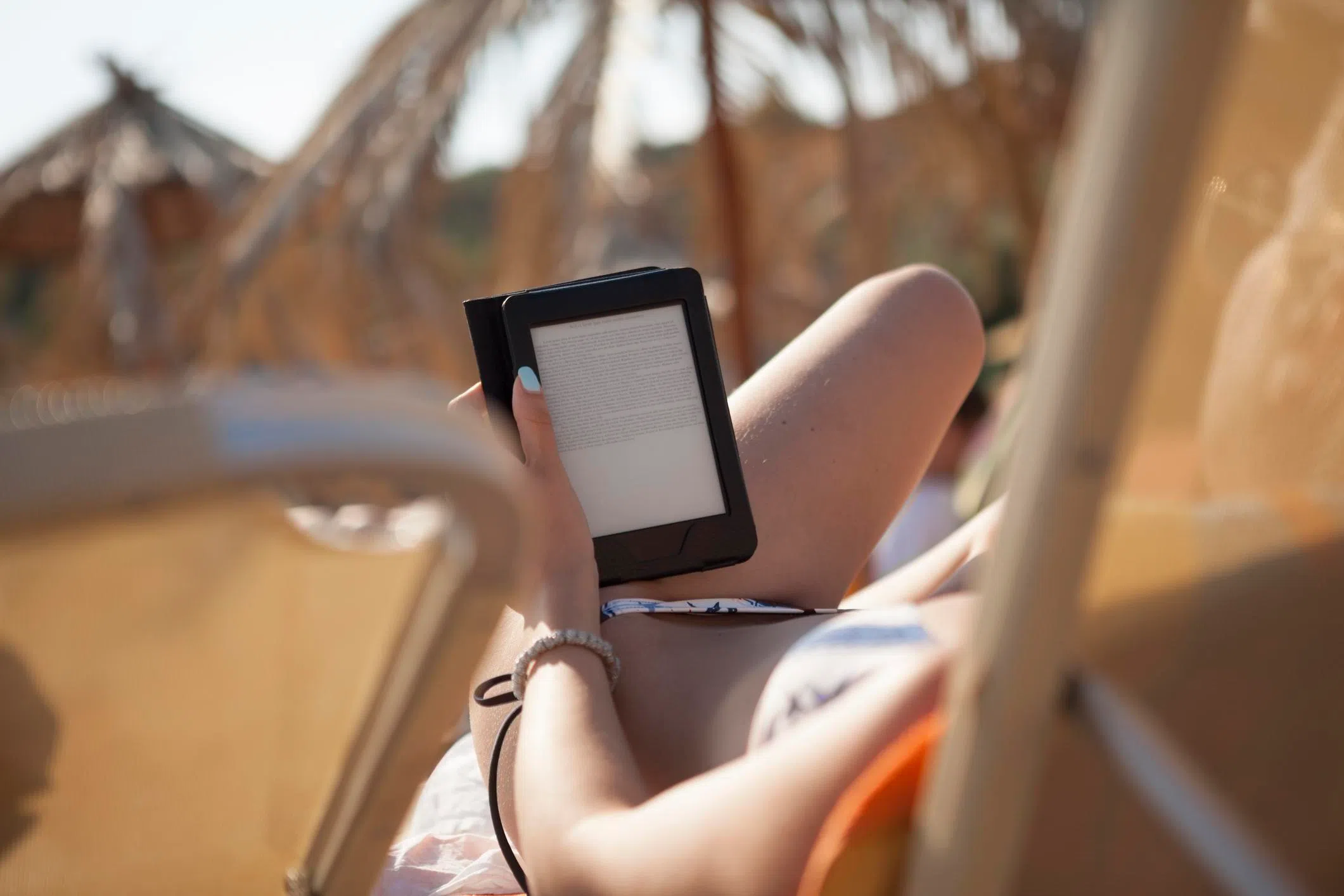 Kobo or Kindle: A woman reading an e-book on the beach