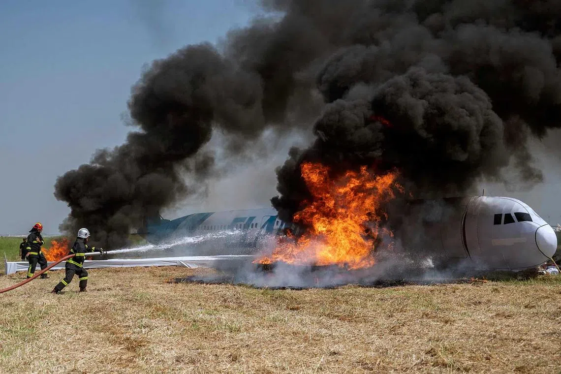 Rescue personnel extinguish a fire in a mock airplane during an emergency response drill simulating an aircraft crash landing at the Juanda international airport in Surabaya on May 17.