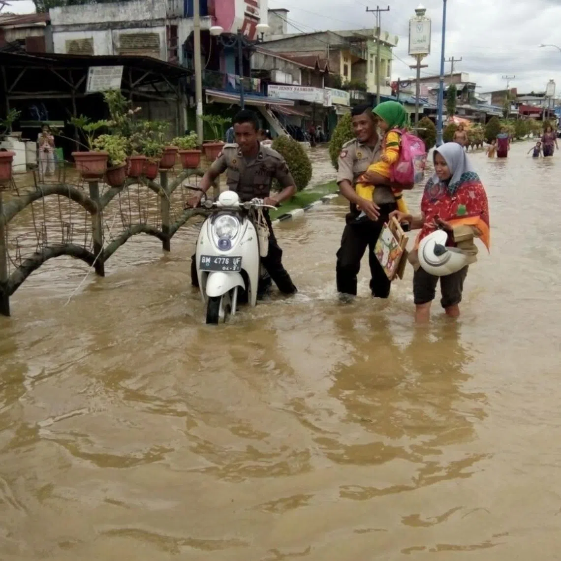 People walk through a flood in Riau in 2025. High rainfall in the past few days has caused floods in dozens of villages and sub-districts in three regencies.