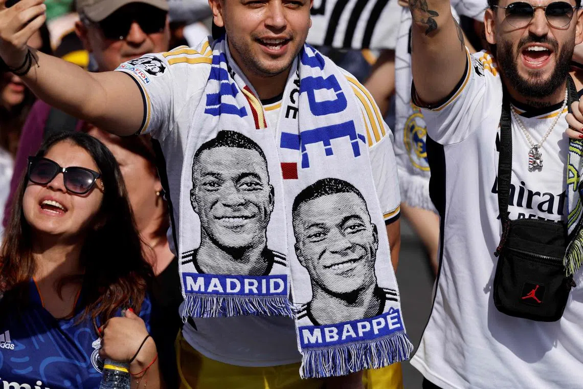 Supporters wearing football scarves depicting French footballer Kylian Mbappe cheer before Real Madrid's celebration for winning 2024 Spanish La Liga title at Cibeles square in Madrid on May 12. Mbappe signed for Real on June 3.