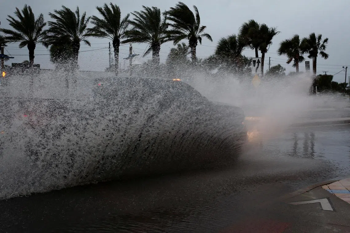 FILE PHOTO: A car drives by a flooded street ahead of the expected arrival of Hurricane Nicole, in Daytona Beach, Florida, U.S., November 9, 2022. REUTERS/Marco Bello/File Photo