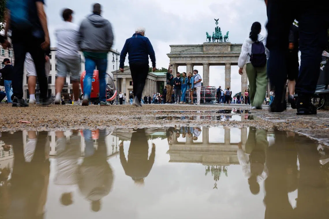 epa12333727 People pass by a puddle in front of the Brandenburg Gate landmark in Berlin, Germany, 29 August 2025.  EPA/CLEMENS BILAN