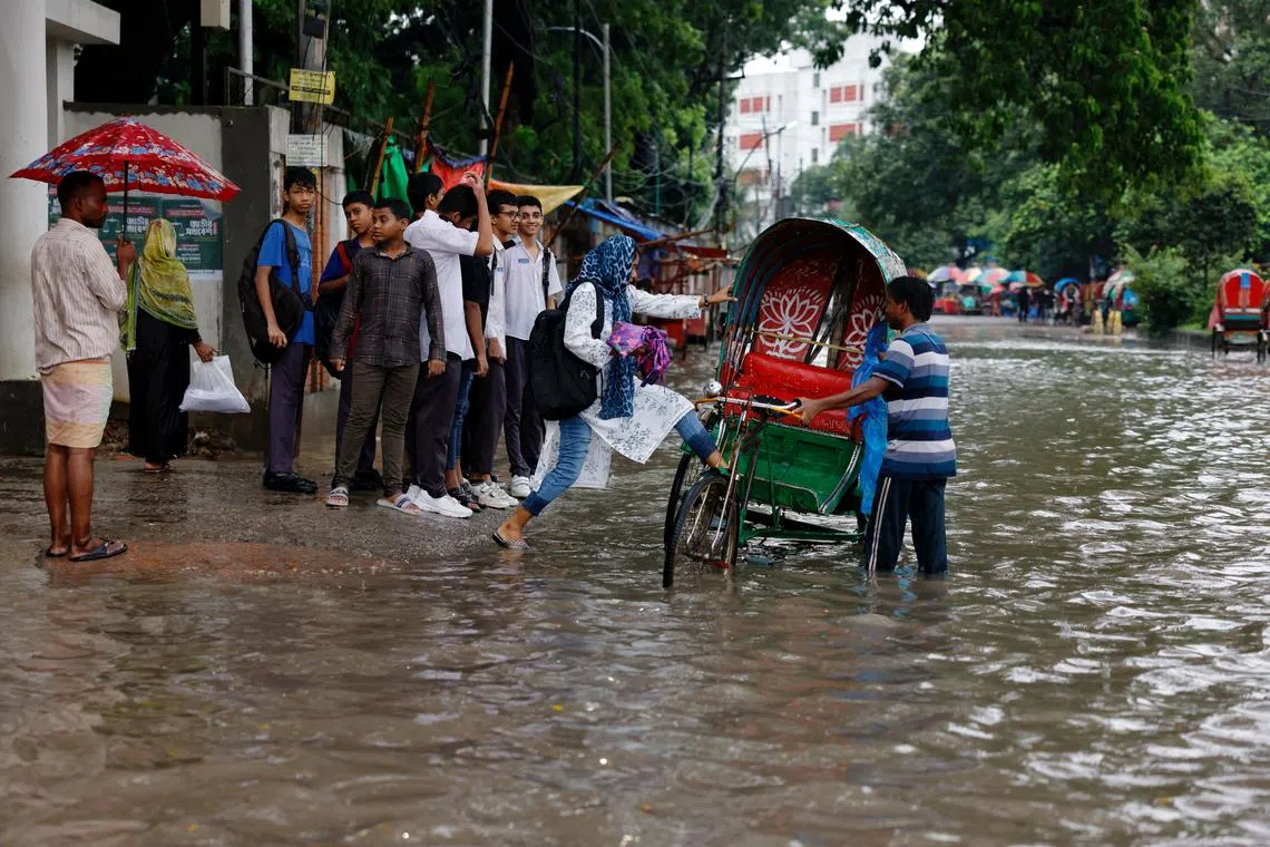 A girl getting on a rickshaw on a street flooded due to heavy rain, in Dhaka, Bangladesh, on July 15, 2025. 