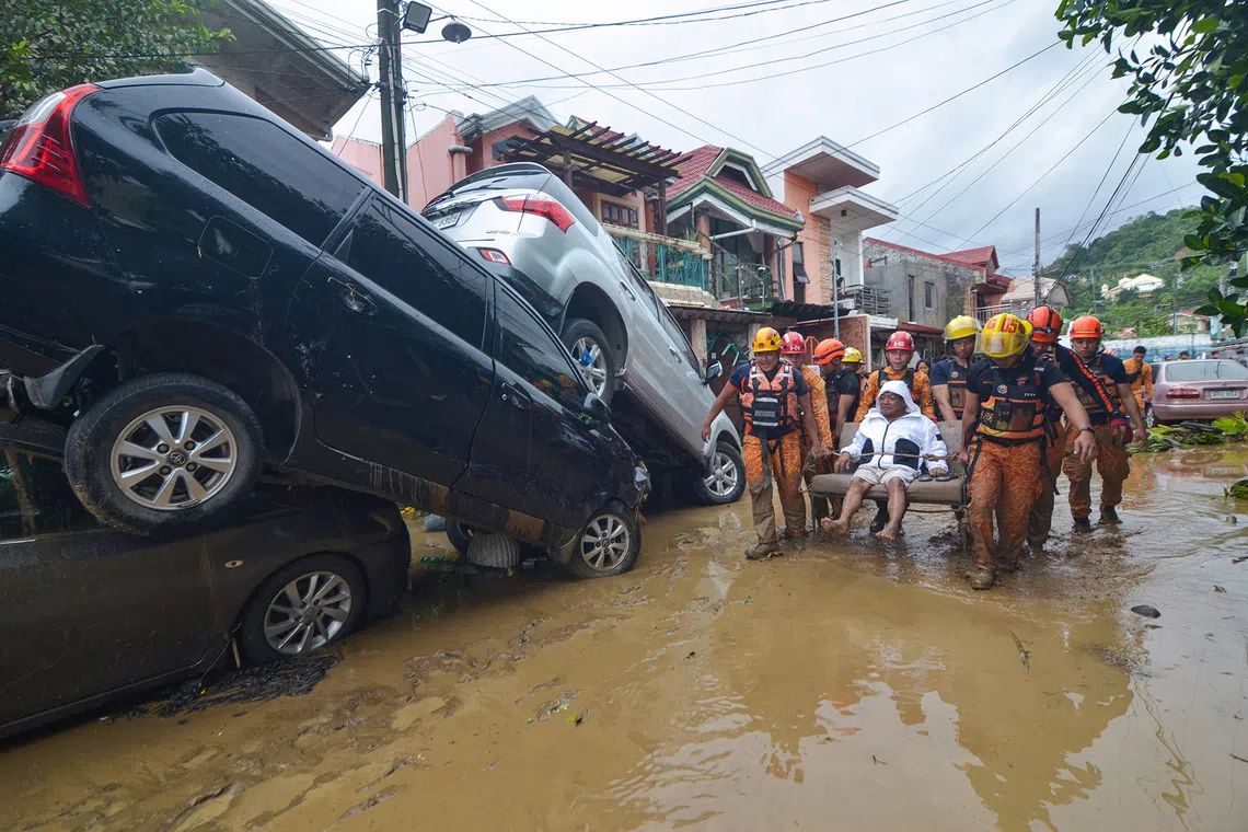 Rescuers carrying a resident past cars washed away by floods at the height of Typhoon Kalmaegi at a subdivision of Cebu City in the central Philippines on Nov 4, 2025. 