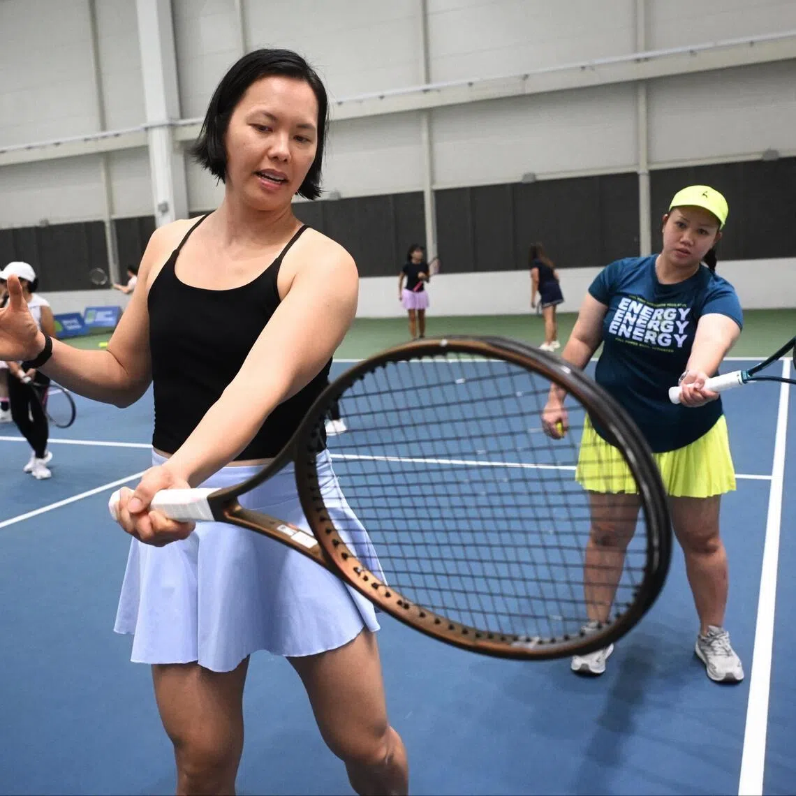 Singapore tennis player Sarah Pang (left) coaching Retchel Ann Tipones of the Philippines during a clinic for domestic helpers at Kallang Tennis Hub on Sept 21.