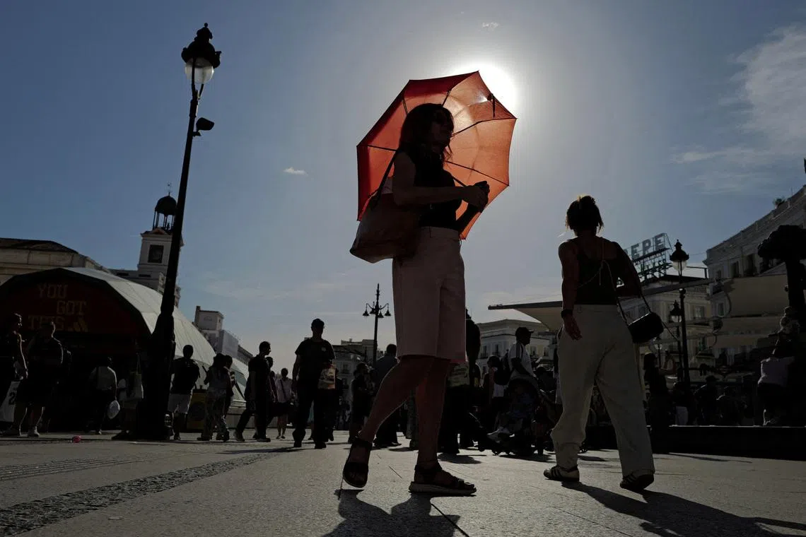 FILE PHOTO: A woman with an umbrella walks at Plaza Puerta del Sol during a spring heatwave in Madrid, Spain, May 27, 2026. REUTERS/Kacper Pempel/File Photo
