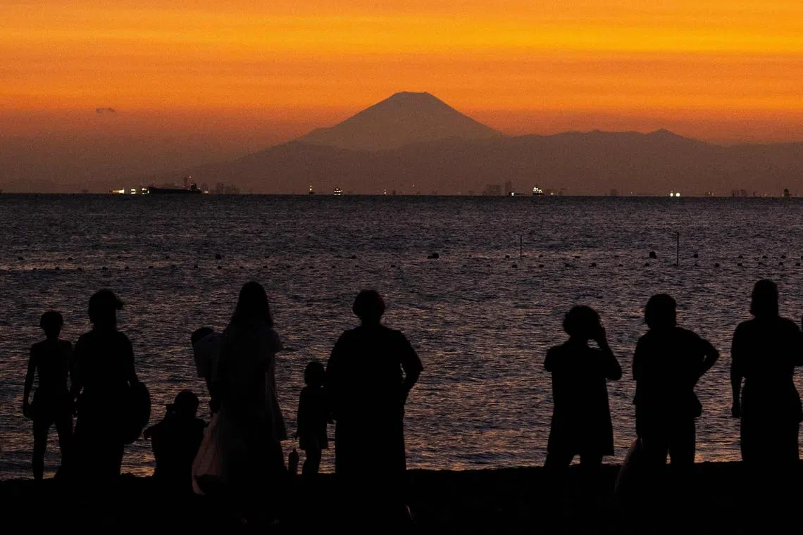 People gather on the beach as Mount Fuji is seen in the background from Inage Seaside Park in Chiba city, a suburb of Tokyo during evening hour on July 29, 2025. (Photo by Philip FONG / AFP)
