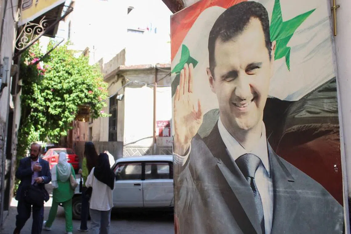 FILE PHOTO: People walk near a poster depicting Syria's President Bashar al-Assad in Damascus, Syria May 19, 2023. REUTERS/Firas Makdesi