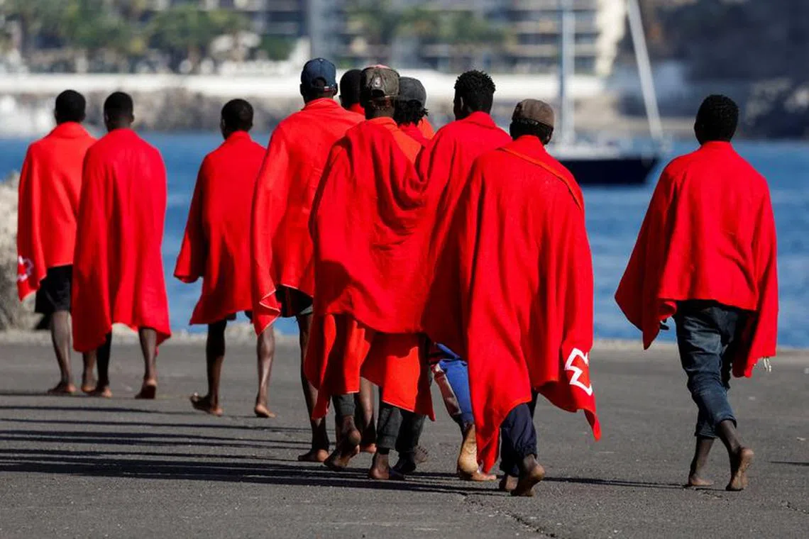 FILE PHOTO: A group of migrants walk in the port of Arguineguin to be assisted by the Red Cross after disembarking from a Spanish coast guard vessel, in the island of Gran Canaria, Spain, October 12, 2023. REUTERS/Borja Suarez/File Photo