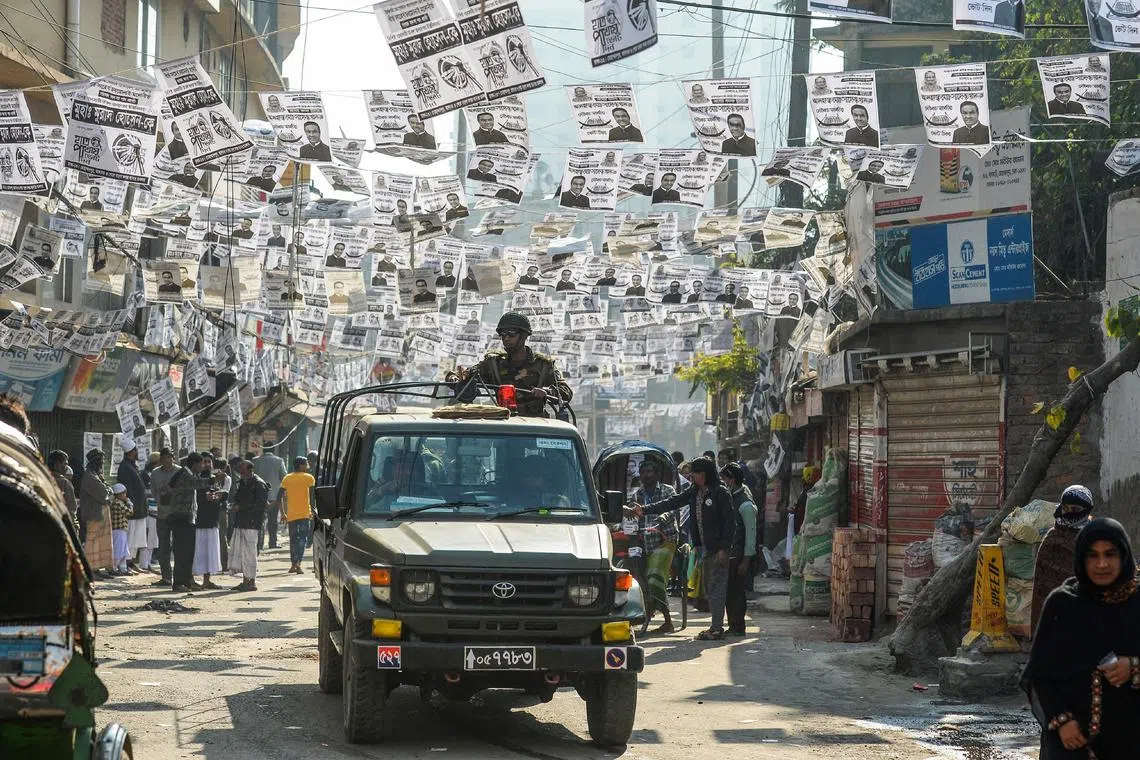 Bangladeshi army personnel drive through a street adorned with election posters near a polling station in Dhaka on Dec 30, 2018.