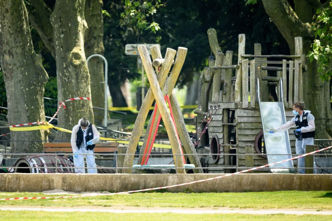 Police officers work inside a cordoned-off area following a knife attack in Annecy, France, on June 8.