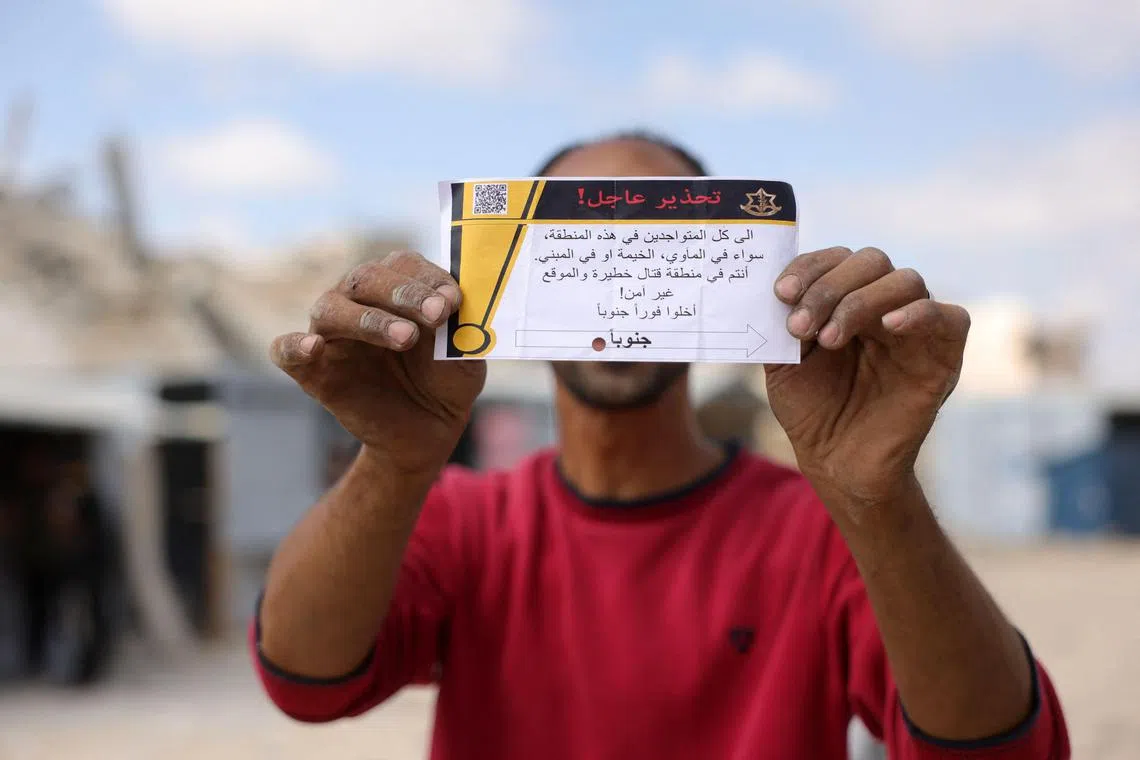 A Palestinian man holding a leaflet dropped by the Israeli army, warning people in Jabalia in the northern Gaza Strip to evacuate towards the southern part of the territory, on May 22.