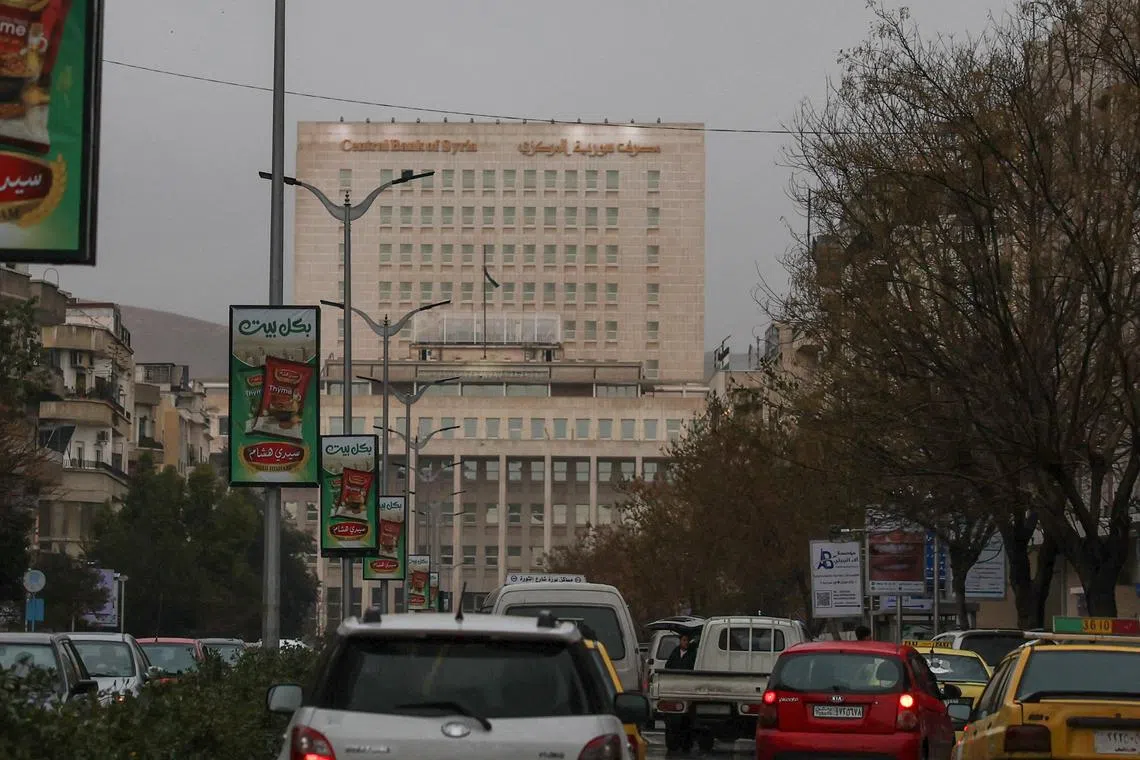 FILE PHOTO: Vehicles drive as the Syrian central bank is seen in the background in Damascus, Syria February 12, 2025. REUTERS/Yamam al Shaar/File Photo
