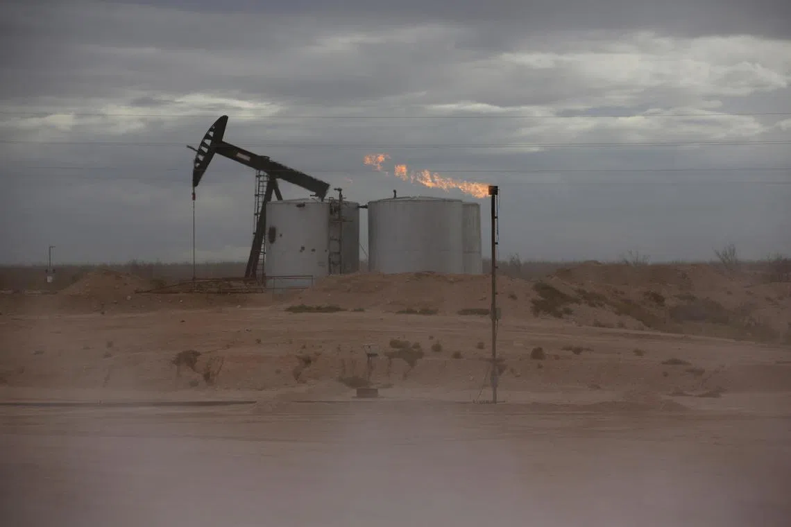 FILE PHOTO: Dust blows around a crude oil pump jack and flare burning excess gas at a drill pad in the Permian Basin in Loving County, Texas, U.S. November 25, 2019. REUTERS/Angus Mordant/File Photo