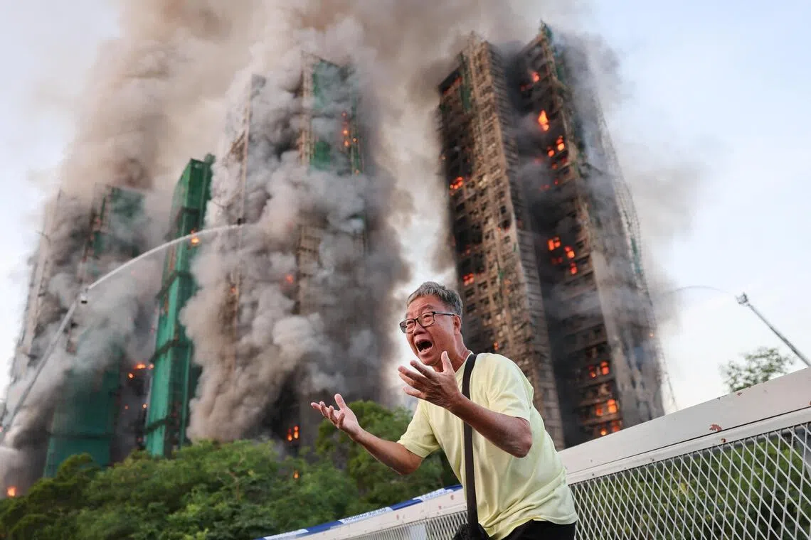 A man reacts, as smoke rises while flames engulf bamboo scaffolding across multiple buildings at Wang Fuk Court housing estate, in Tai Po, Hong Kong, China, November 26, 2025. REUTERS/Tyrone Siu