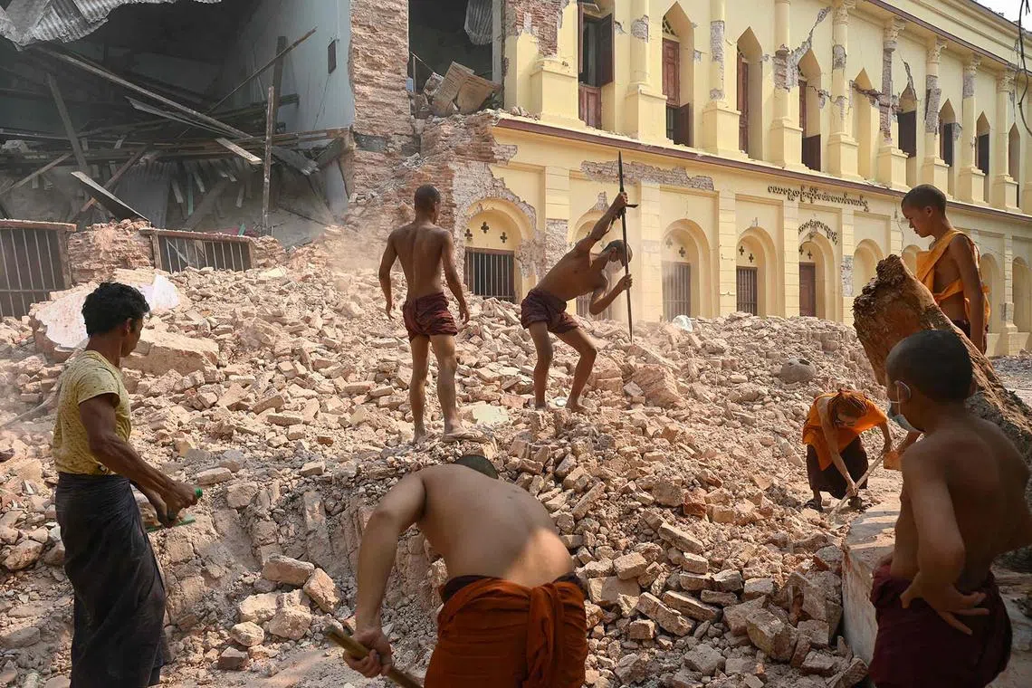 TOPSHOT - Buddhist monks clear up rubble at the damaged Thahtay Kyaung Monastery in Mandalay on April 1, 2025, four days after a major earthquake struck central Myanmar. Four days after the shallow 7.7-magnitude earthquake that killed more than 2,000 people, many people in Myanmar are still sleeping outdoors, either unable to return to ruined homes or afraid of further aftershocks. (Photo by Sai Aung MAIN / AFP)