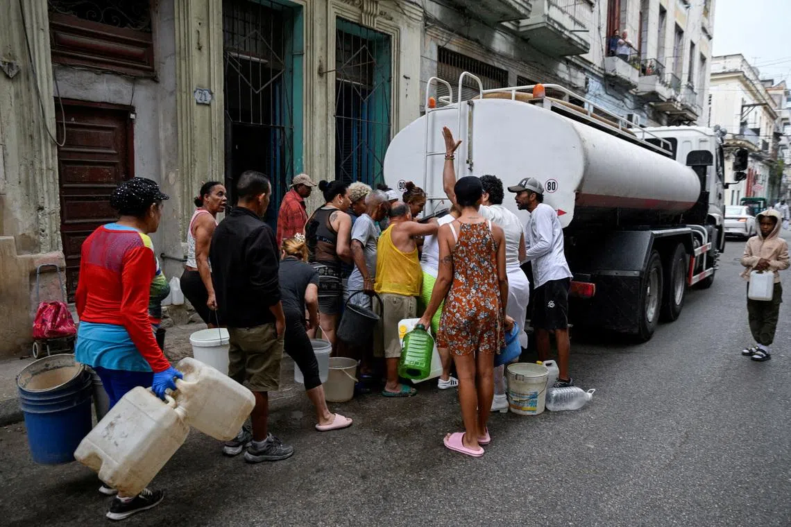 FILE PHOTO: People gather around a water tanker truck to fill up buckets and other containers as severe fuel shortages have disrupted water pumping and distribution, in Havana, Cuba March 19, 2026. REUTERS/Norlys Perez/File Photo